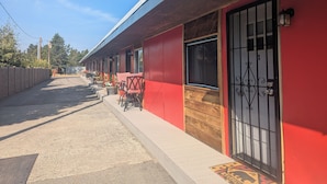A row of rooms with individual doors, a red exterior wall, and a wooden door frame. - Yellowstone Studio # 3. Just One Mile From Yellowstone's Main Entrance (West Yellowstone)