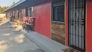 A row of rooms with a red exterior, wooden door frames, and a gated entrance. - Yellowstone Studio # 3. Just One Mile From Yellowstone's Main Entrance (West Yellowstone)