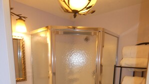 A bathroom with a glass-enclosed shower, a toilet with a paper towel holder, a sink, and a mirror with a gold frame. - Yellowstone Studio # 3. Just One Mile From Yellowstone's Main Entrance (West Yellowstone)