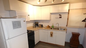 A compact kitchen with white cabinets, a refrigerator, a stove, a microwave, and a sink. - Yellowstone Studio # 3. Just One Mile From Yellowstone's Main Entrance (West Yellowstone)