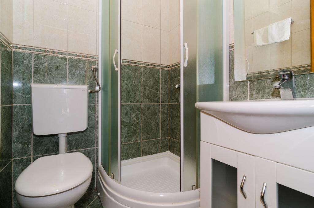 A bathroom with a toilet, a shower enclosure, and a sink.