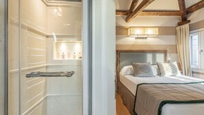 Ein Hotelzimmer mit Dusche, einem Bett mit Kopfteil und einem Fenster mit Vorhängen.