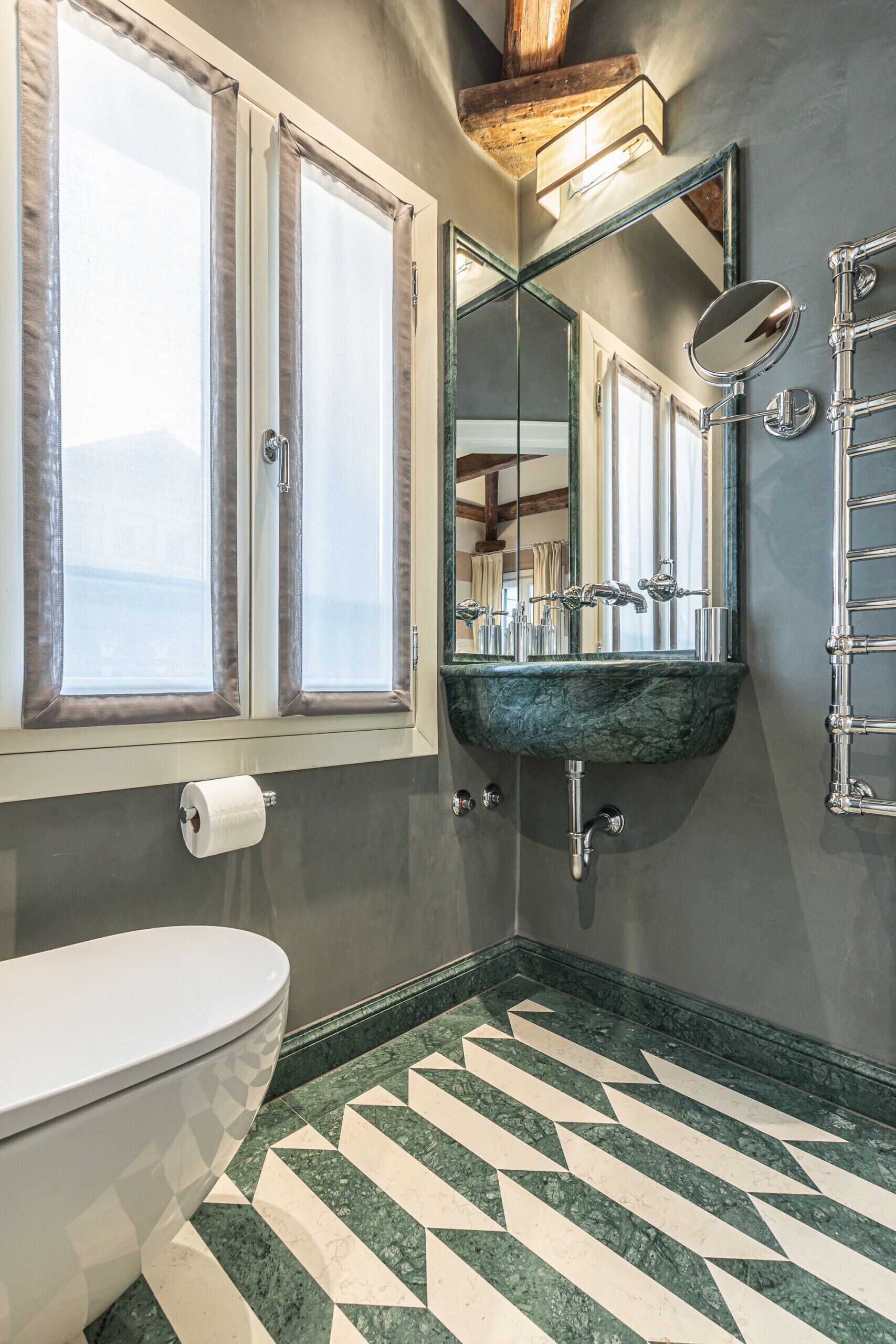 A bathroom with a toilet, a sink with a mirror, and a window with curtains.