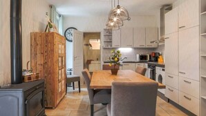 A modern kitchen with a dining area, featuring a wooden cabinet, a stove, and a dining table with chairs.