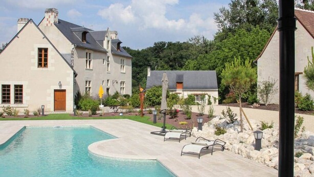 A swimming pool with a curved edge, surrounded by a paved deck and stone landscaping.