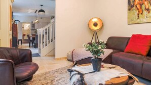 A living room with a sofa, a coffee table with a plant, a floor lamp, and a painting on the wall.