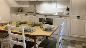 Eine moderne Küche mit weißen Schränken, einem Holzespeisetisch für vier Personen und einem fliesenbelagten Boden mit Muster.