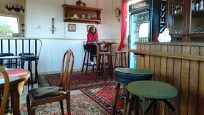 A cozy bar area with wooden furniture, a Guinness refrigerator, and a variety of bottles on shelves. - Mlima View Gardens (Nanyuki)