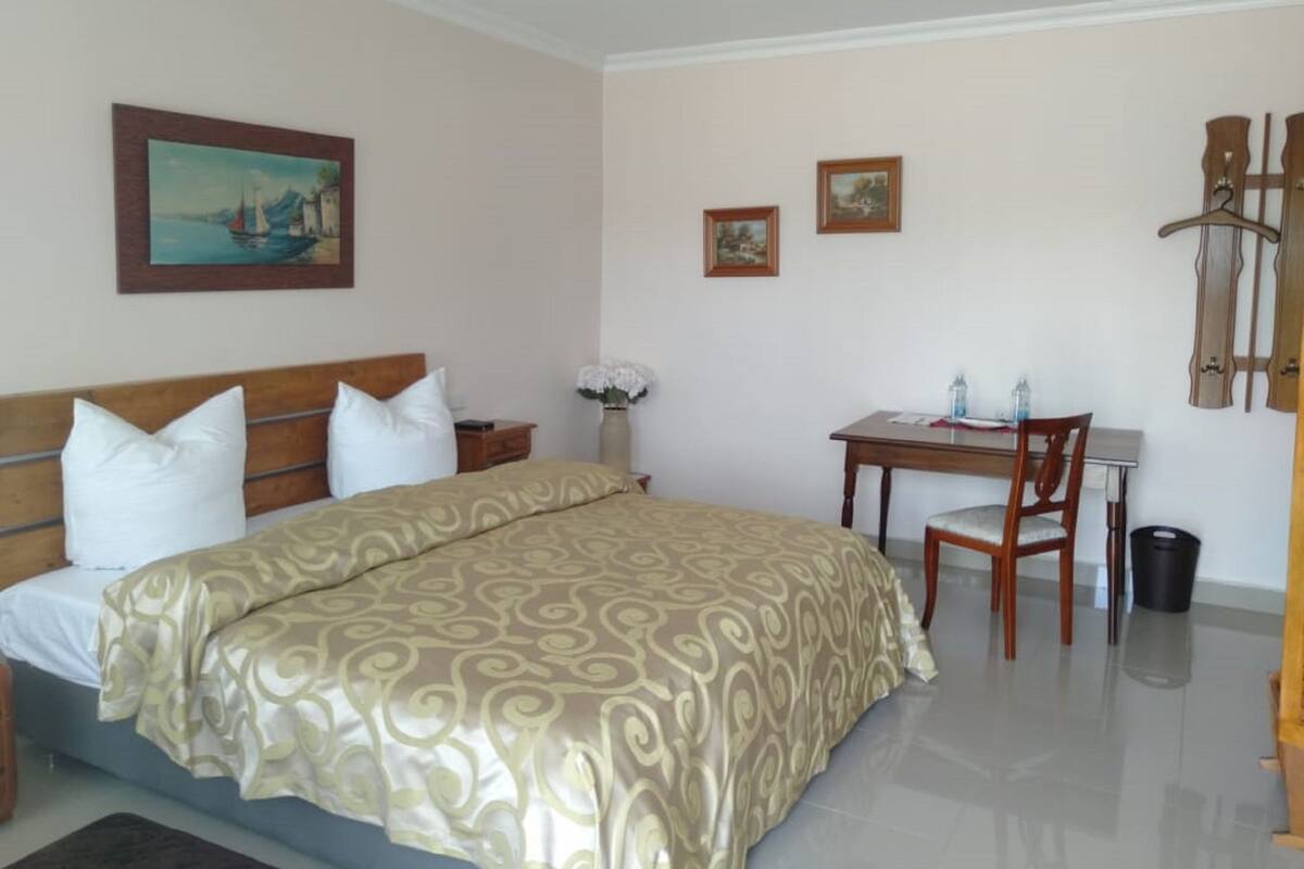 A hotel room with a bed, a desk, and a chair.