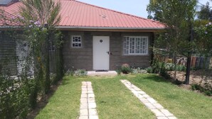 A single-story house with a red roof, a front door, and a small window. - Mlima View Gardens (Nanyuki)