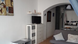 A modern living room with a grey sofa, a small white table, and a TV on a cabinet. - Studio Rosas Spain (ROSES)