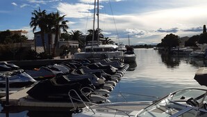 A marina with boats docked, a clear sky, and palm trees. - Studio Rosas Spain (ROSES)