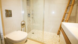 A bathroom with a toilet, a glass-enclosed shower, and a wooden ladder. - Modern Studio 1 minute from La Croisette (Cannes)