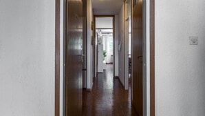 A narrow hallway with white walls and wooden doors, leading to a staircase and a room with a plant. - Apartment Gordana (ST) - One Bedroom Apartment (Split)