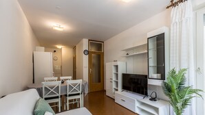 A modern living room with a sofa, TV, and a dining area with a table and chairs. - Apartment Gordana (ST) - One Bedroom Apartment (Split)