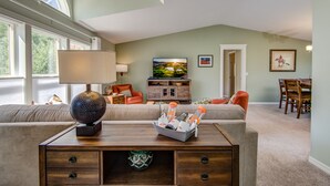 A spacious living room with a large window, a television, and a dining area. - Experience breathtaking views at Sedona Thunder Mountain Cottage, a spacious 3-bedroom retreat. (Sedona)