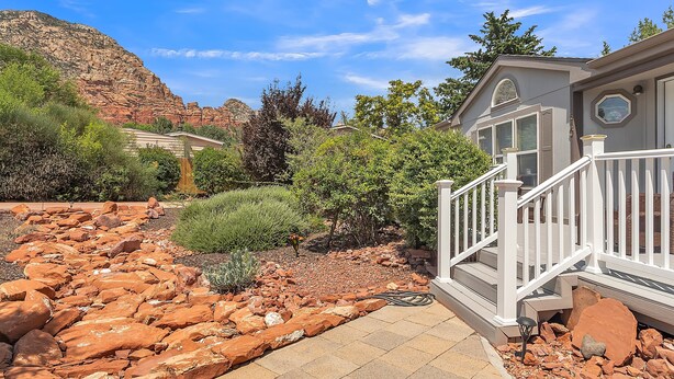 A residential property with a paved driveway, a white staircase, and a garden with red rocks and greenery. - Experience breathtaking views at Sedona Thunder Mountain Cottage, a spacious 3-bedroom retreat. (Sedona)