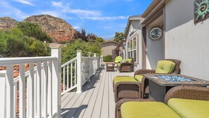 A deck with wicker furniture and a table, overlooking a mountainous landscape. - Experience breathtaking views at Sedona Thunder Mountain Cottage, a spacious 3-bedroom retreat. (Sedona)