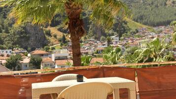 Una terraza con muebles de mimbre y vistas a un pueblo en la ladera.