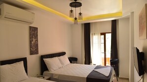 Et hotelværelse med to senge, en ventilator, aircondition, et maleri, et fjernsyn og udsigt til det fri.