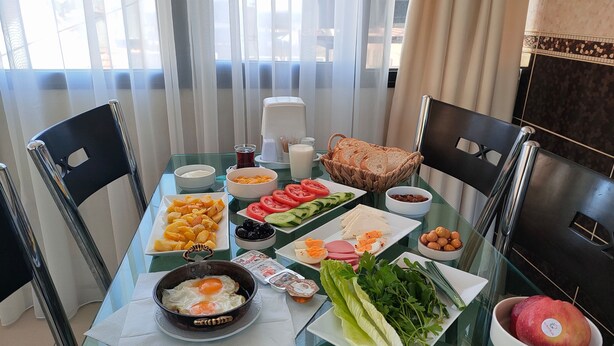 Et morgenbord med forskellige spiser, herunder æg, ost, tomater, agurker og brød.