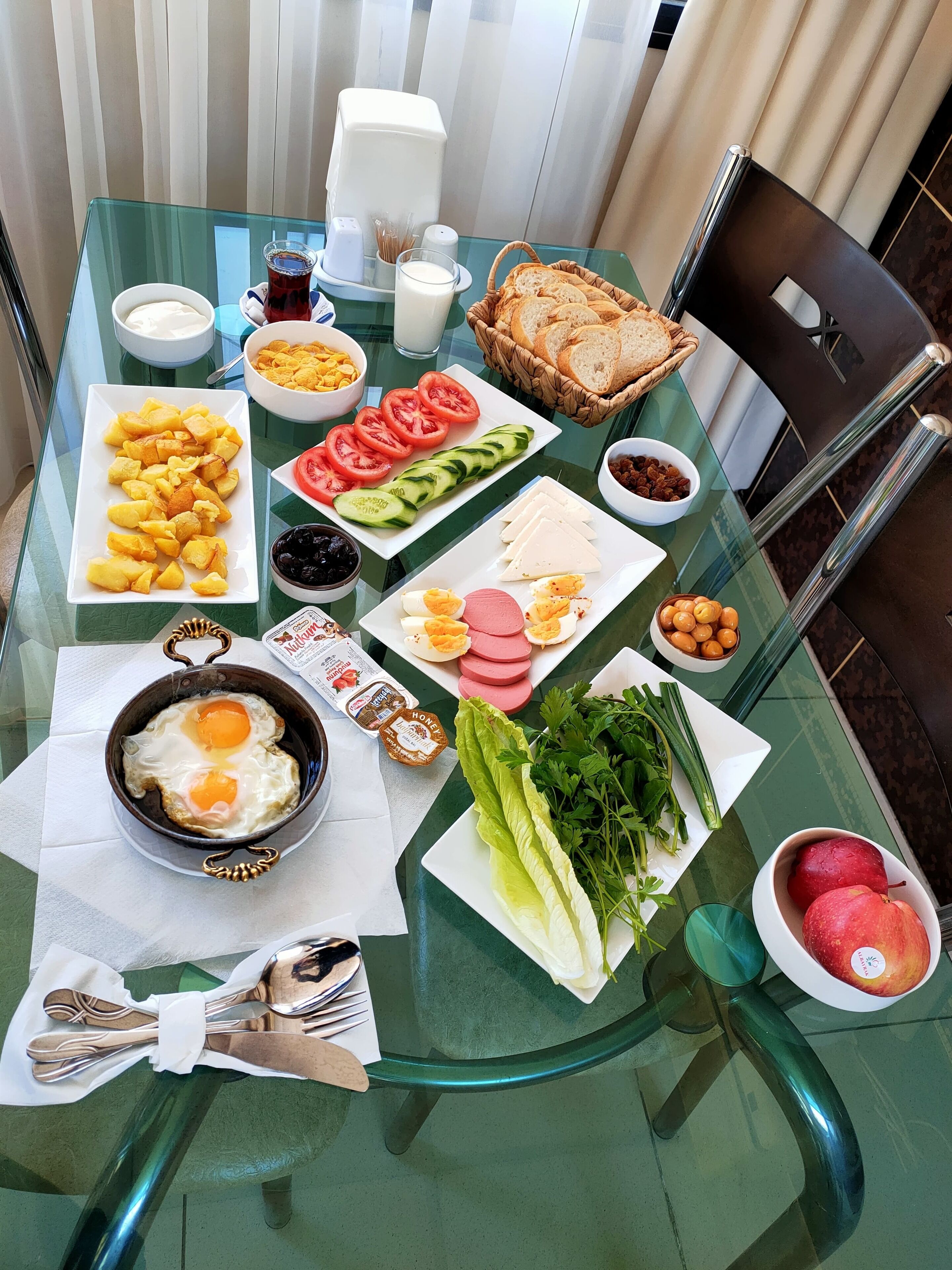 A breakfast table with various food items, including eggs, cheese, bread, and fruits.