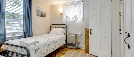 A bedroom with a bed, a heater, a window with curtains, and a door.
