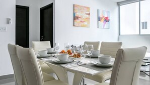 A modern dining room with a white table set for six, surrounded by beige chairs.