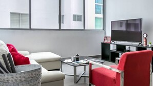 A modern living room with a sofa, red chair, coffee table, and a flat-screen TV.