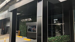 A modern building entrance with a black facade and a sign that reads "POURIER."