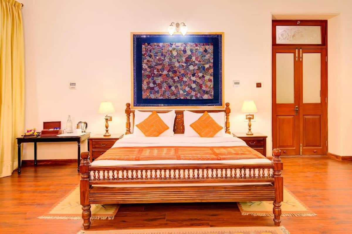Une chambre à coucher bien rangée, avec un grand lit, deux tables de chevet avec des lampes, une porte en bois et une œuvre d’art encadrée au mur.
