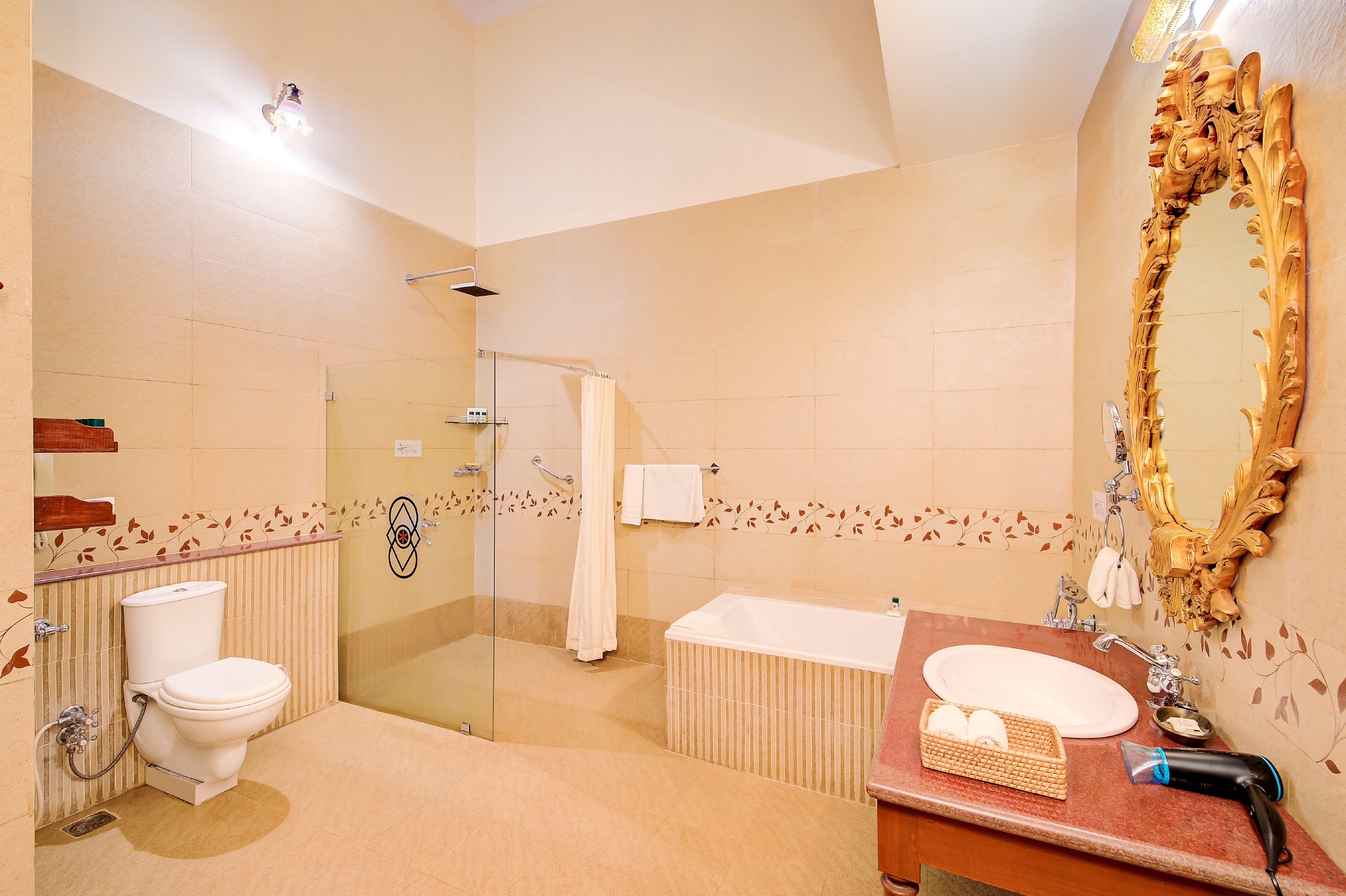 A bathroom with a glass shower enclosure, a toilet, a sink with a vanity, and a large ornate mirror.