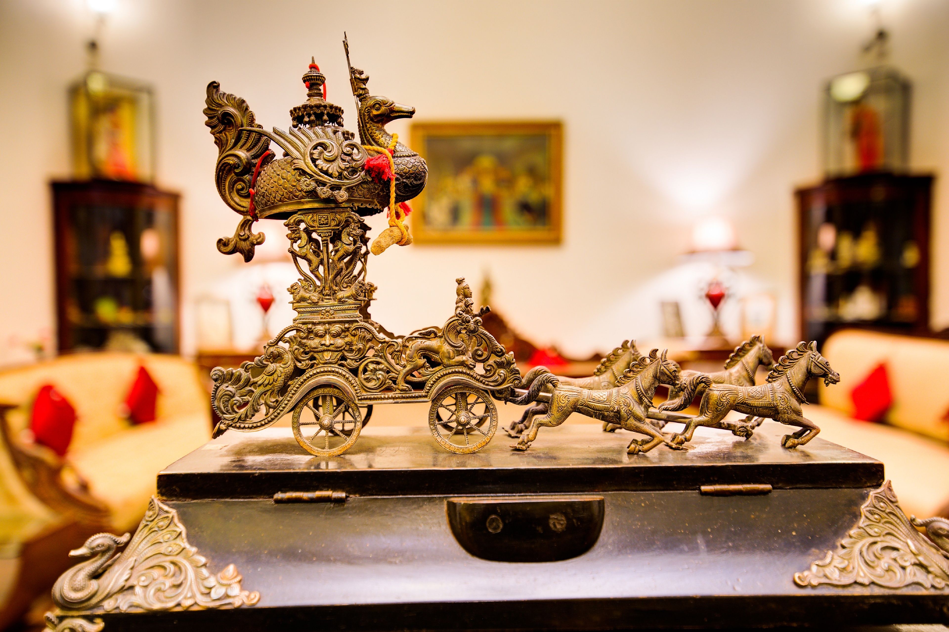 Un cofre decorativo con elaboradas tallas y un modelo de carruaje tirado por caballos.