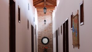 Um corredor com parede de tijolos, um espelho redondo e um lustre.