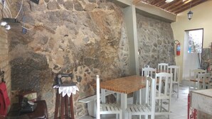 Um interior rústico com paredes de pedra, móveis de madeira branca e um rádio antigo.