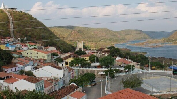 A coastal town with colorful buildings, a prominent church, and a view of the sea. - Pousada Asa Branca (Piranhas)