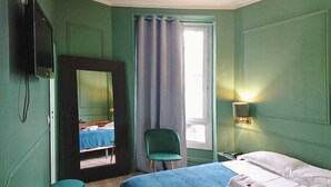 Quarto com cama, cadeira, espelho, televisão e janela com cortinas.