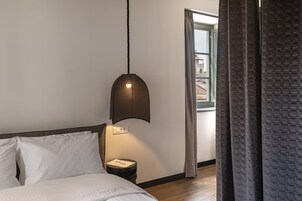 Una camera da letto con un letto, un comodino, una lampada e una finestra con tende.