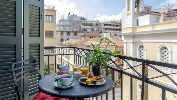 Uma varanda com uma mesa posta para o café da manhã, incluindo doces, café e suco de laranja.