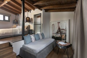 Una camera da letto moderna con un letto grande, un divano, un tavolino e un quadro appeso alla parete.