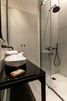 A modern bathroom with a glass-enclosed shower, a round sink, and a black countertop.