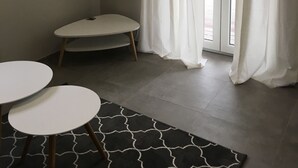 Une pièce avec une table d’angle, une petite table ronde et un tapis à motifs.