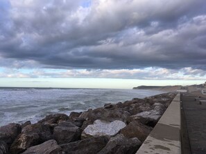 A rocky shoreline with a concrete walkway leading to a building.