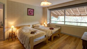 A bedroom with two wooden beds, a window with a wooden roof, and a hanging light fixture. - Spacious cottage with private pool and pets allowed in Saint-Priest-la-Prugne (Saint-Priest-la-Prugne)