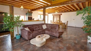 A spacious living area with a brown sectional sofa, a stone coffee table, and a dining table with chairs. - Spacious cottage with private pool and pets allowed in Saint-Priest-la-Prugne (Saint-Priest-la-Prugne)