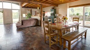 A spacious dining area with a wooden table and benches, a kitchen in the background, and a large sliding glass door leading to an outdoor patio. - Spacious cottage with private pool and pets allowed in Saint-Priest-la-Prugne (Saint-Priest-la-Prugne)