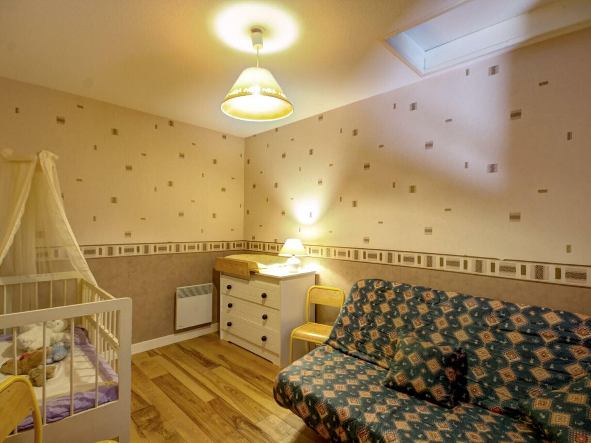 A child's room with a crib, a desk, and a patterned sofa.