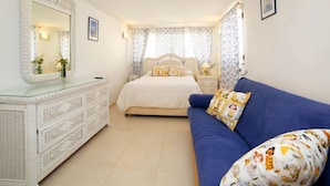 Une chambre à coucher avec un grand lit, une commode, un canapé bleu et des rideaux à motifs.