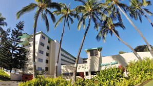 A hotel with a modern design, palm trees, and a well-maintained garden.