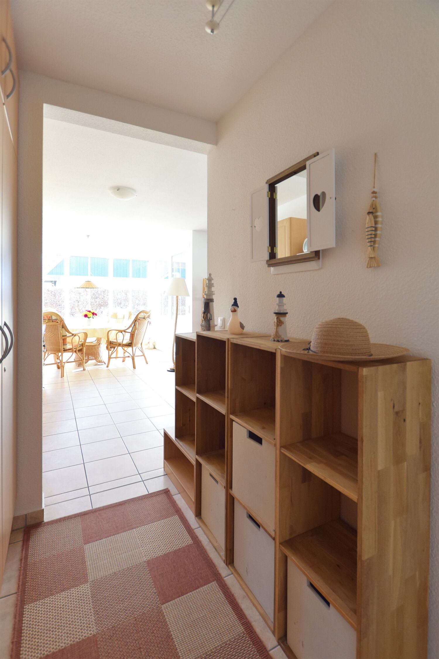 Un couloir avec une console en bois, un miroir et un tapis à motifs.